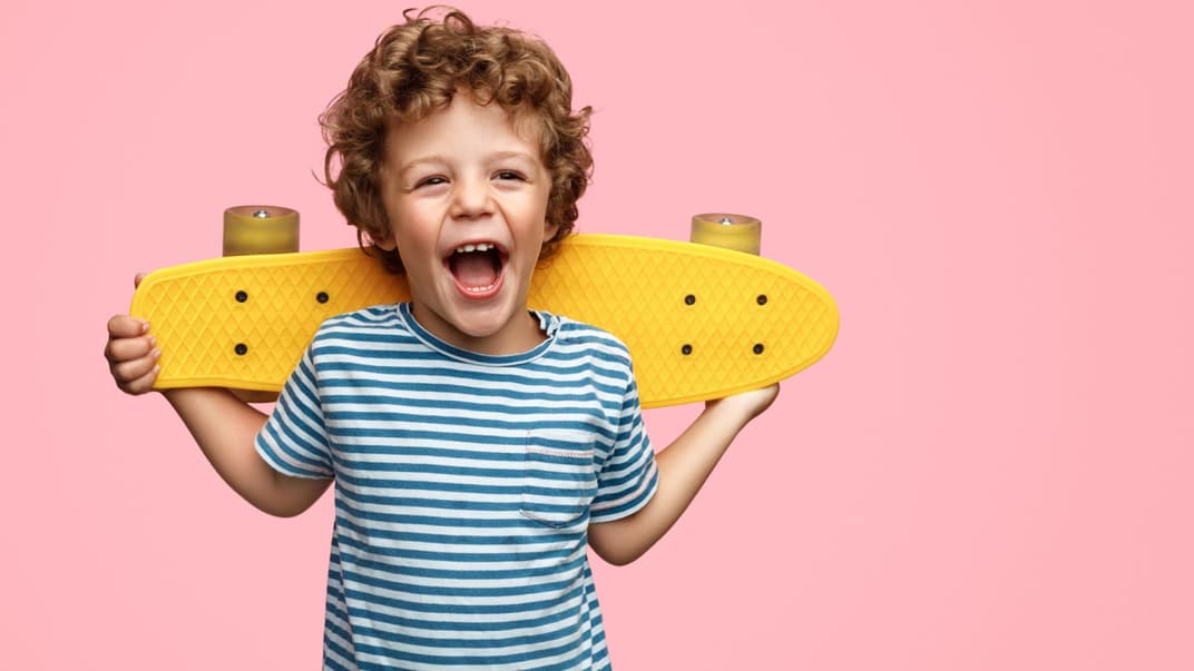 Niedlicher Junge mit gelbem Skateboard.