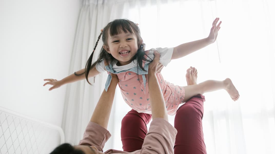 Lachendes Kind wird von Mutter hochhoben.
