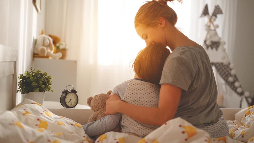 Mutter weckt ihre Tochter morgens im Bett.