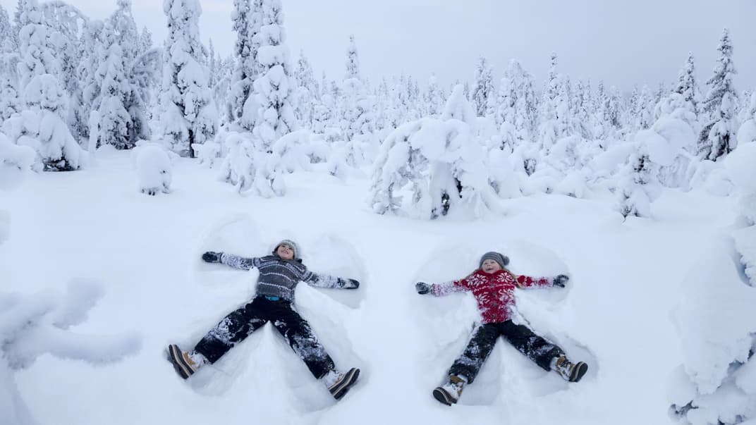 Zwei Kinder machen Schneeengel.