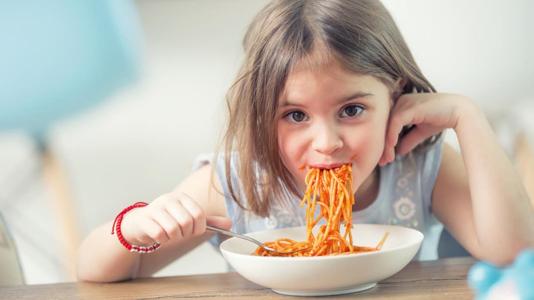 Gemeinsam essen ist schön. Ein Kind, das Spaghetti isst.