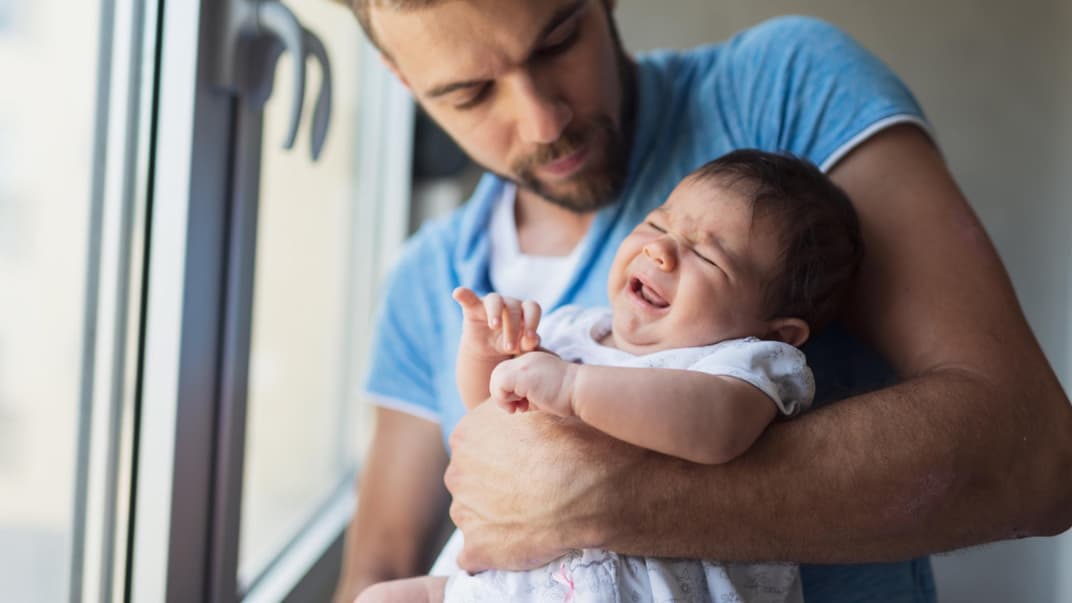 Junger Vater mit Baby auf dem Arm: Papas in Elternzeit müssen sich viele blöde Sprüche anhören.