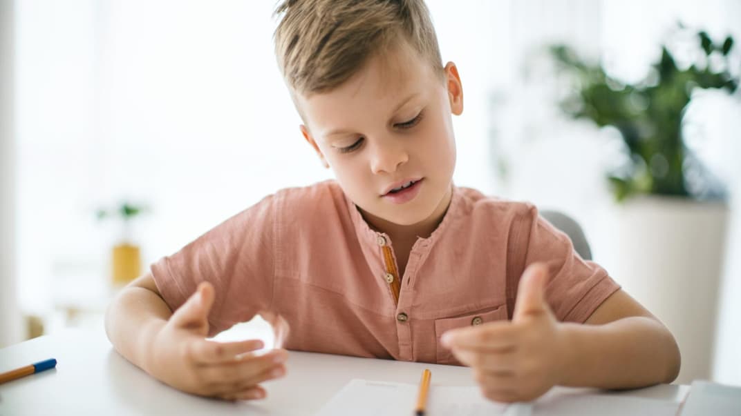 Ein Junge nimmt zum Zählen seine Finger.