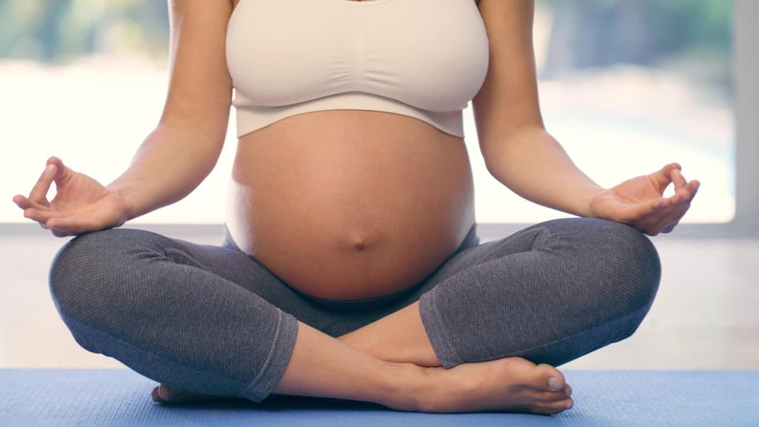 Nahaufnahme von schwangerer Frau beim Yoga.