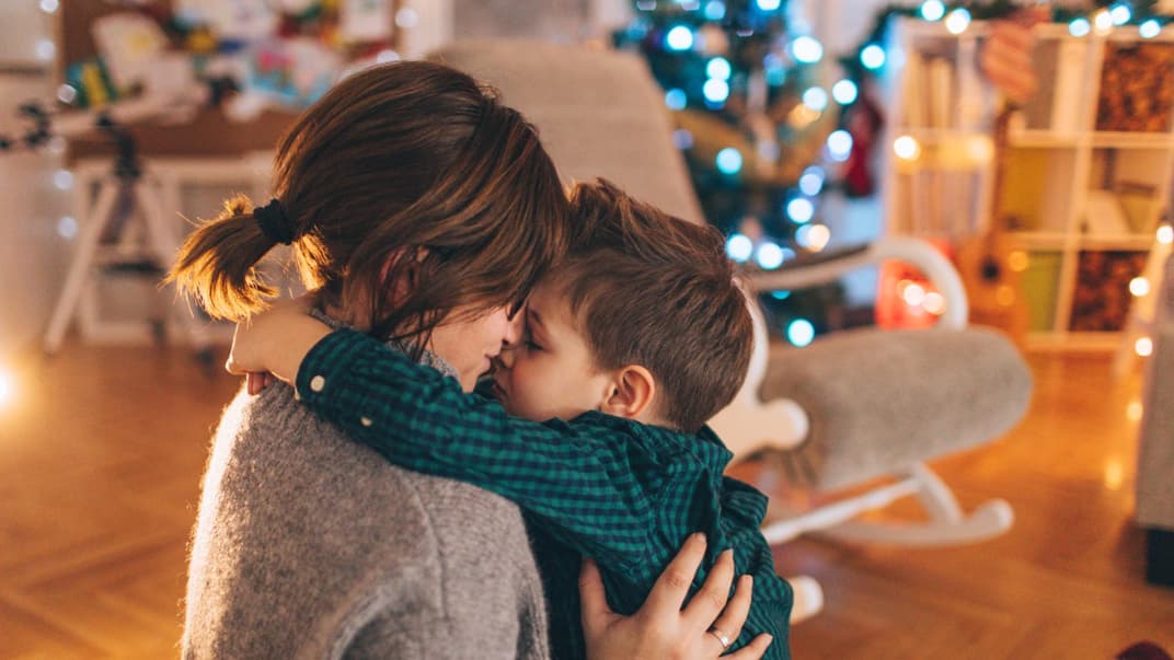 Kleiner Junge kuschelt mit seiner Mama, nachdem sie seine Weihnachtswünsche gelesen hat.