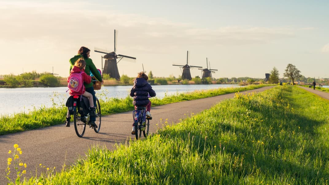 Holländische Familie fährt Fahrrad entlang von niederländischen Windmühlen. 