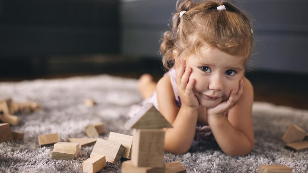 Kleines Mädchen spielt mit Holzbauklötzen.