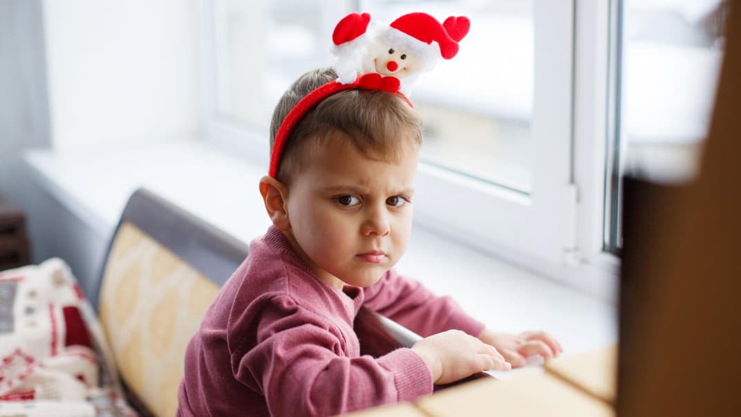 Ein Kind mit Weihnachtsmannhaarreif, der sauer gut