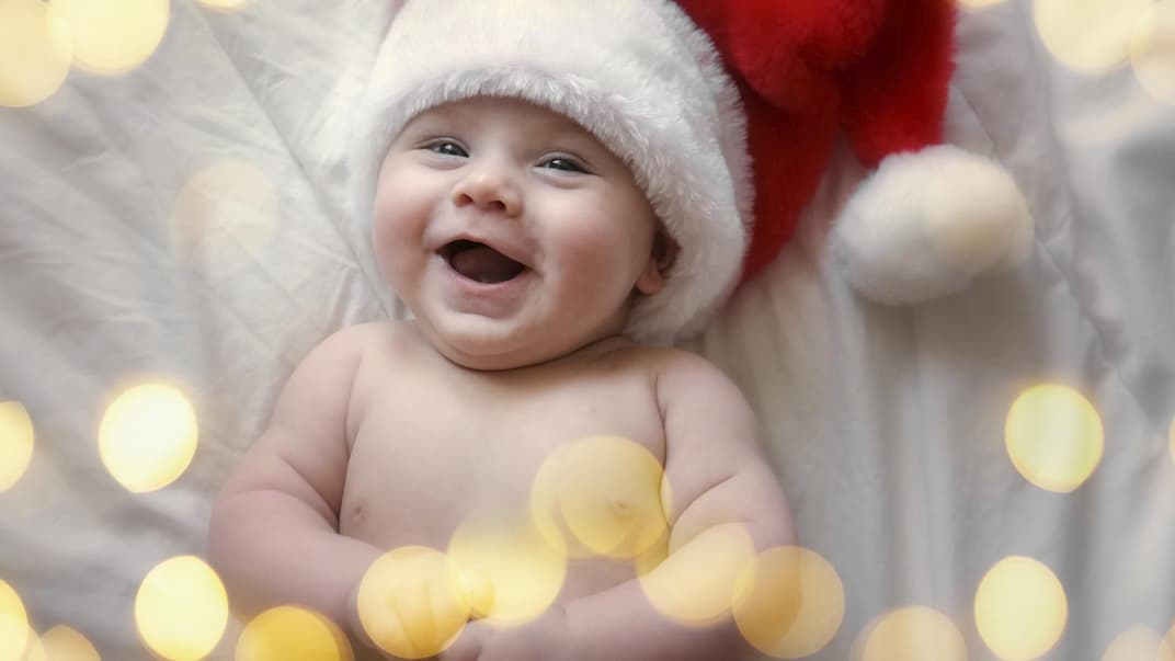 Lachendes Baby mit Weihnachtsmütze.