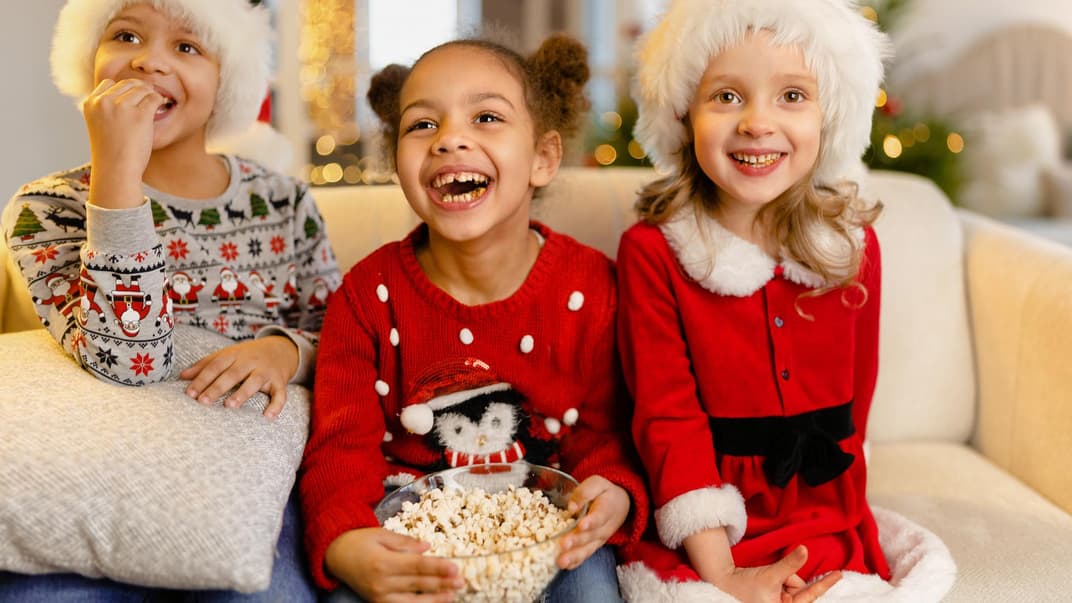 Drei weihnachtliche gekleidete Mädchen vor dem Fernseher.