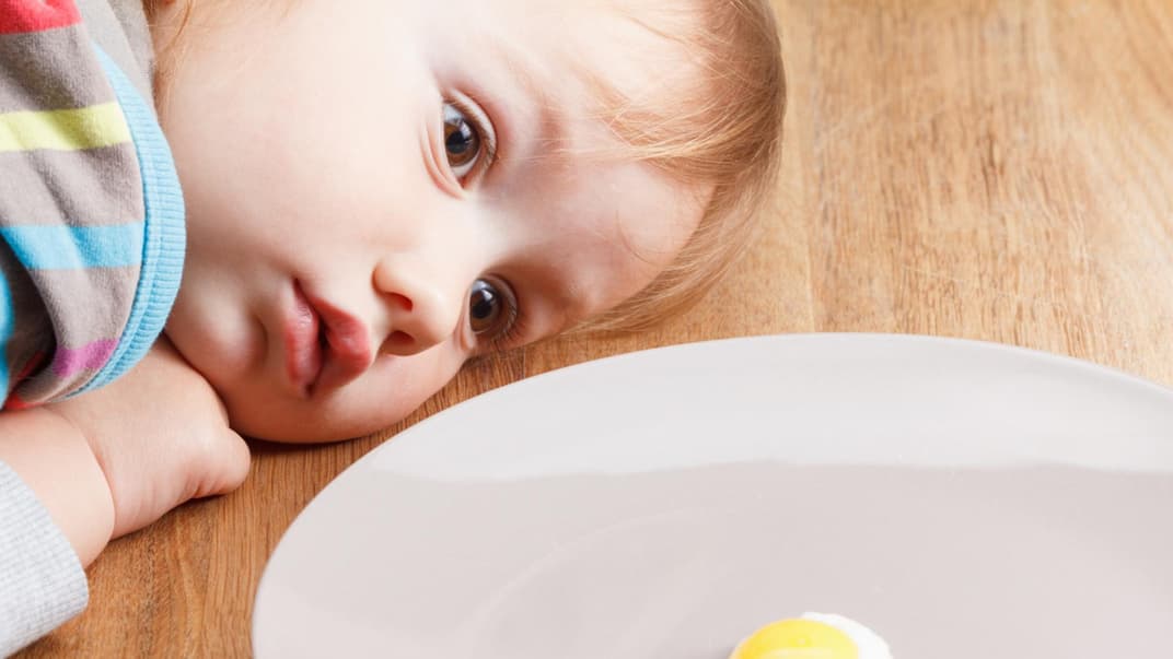 Baby schaut sich ein Spiegelei genau an. 