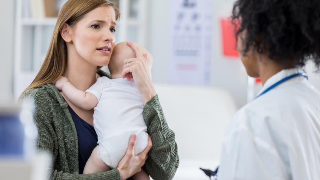 Eine Mutter steht mit ihrem Baby auf dem Arm in der Notfallambulanz. Eine Mutter steht mit ihrem Baby auf dem Arm in der Notfallambulanz.