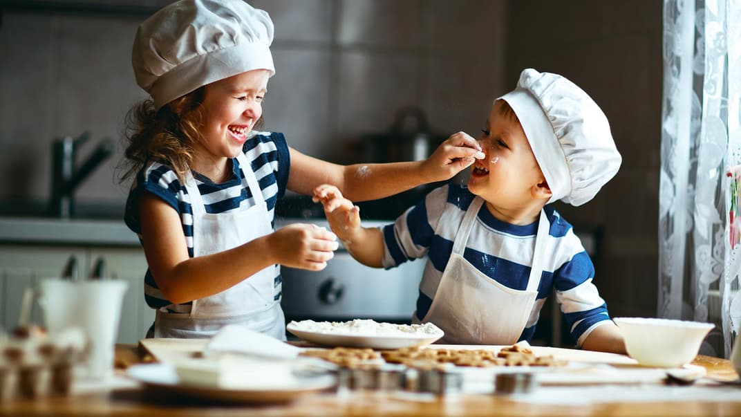 Zwei kleine, niedliche Kinder backen Kekse.