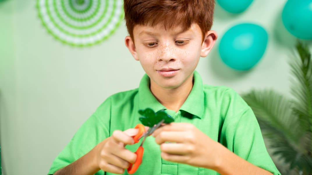 Junge bastelt Kleeblatt als Glücksbringer.