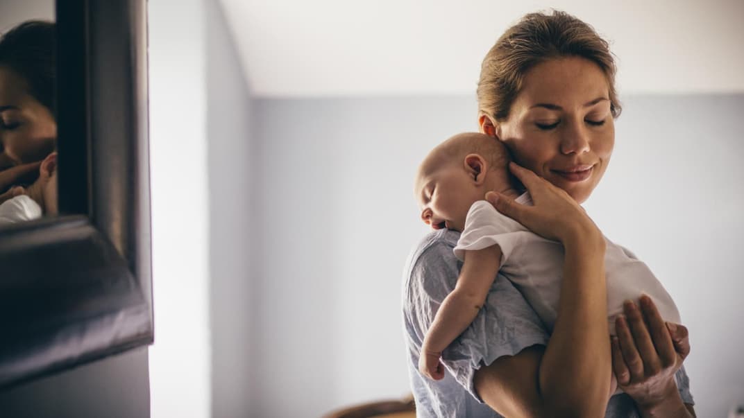 Mama trägt ihr Baby liebevoll im Arm.