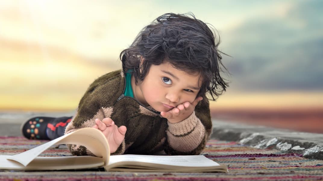 Ernstes Kind schaut von einem Buch hoch.