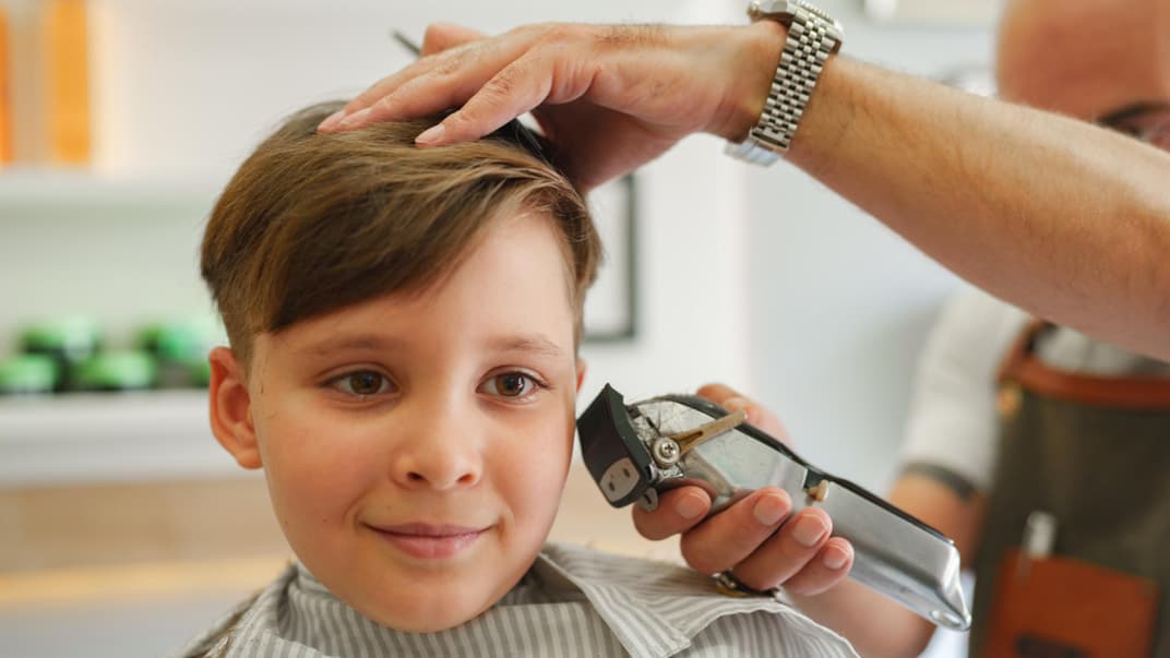Ein Junge, der beim Friseur sitzt. 