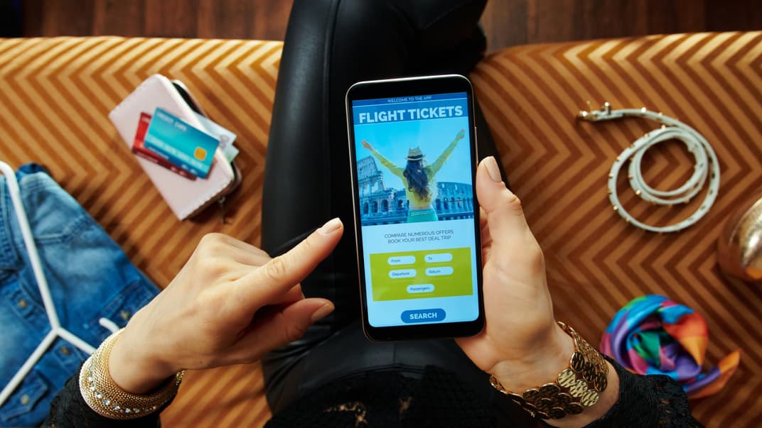 Frau bucht über ihr Handy eine Reise.