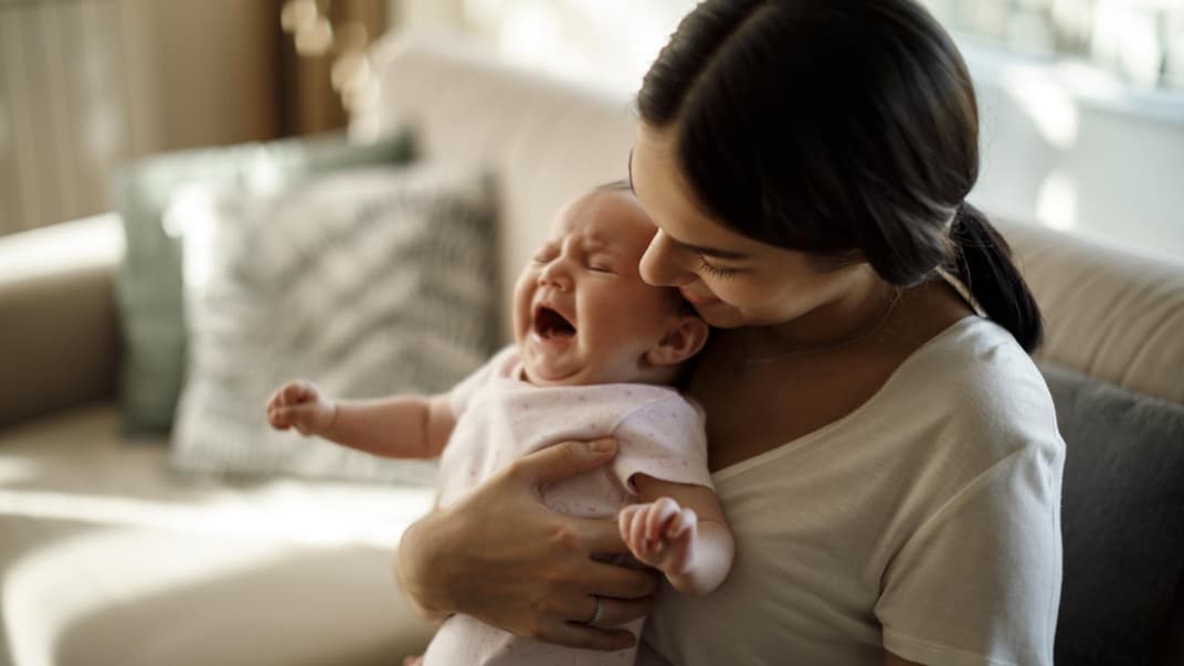 Mama hält zitterndes Baby im Arm.