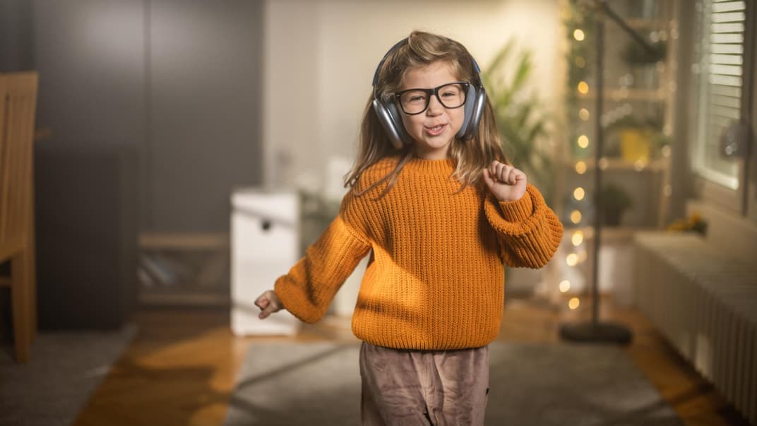 8-Jährige hört Musik mit Kopfhörern und tanzt dabei.
