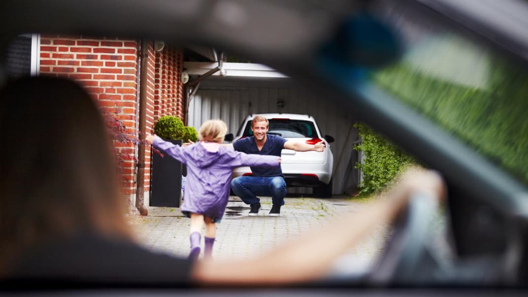 Kind läuft vom Auto der Mama zum Papa.