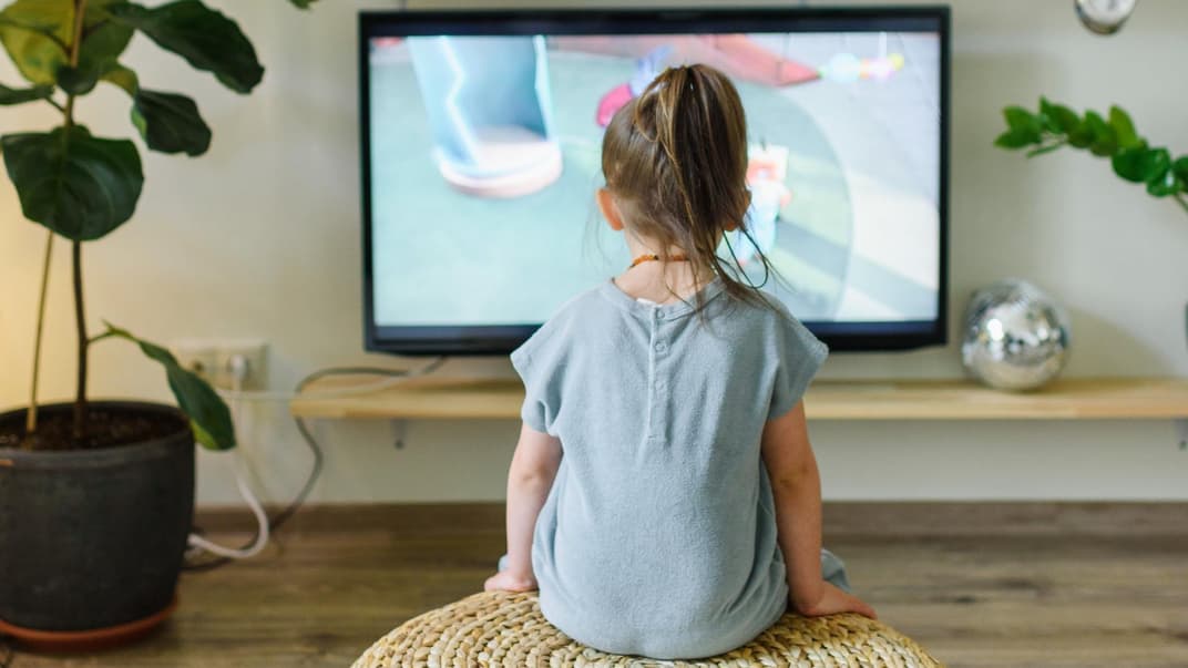 Ein kleines Mädchen guckt Fernsehen. 