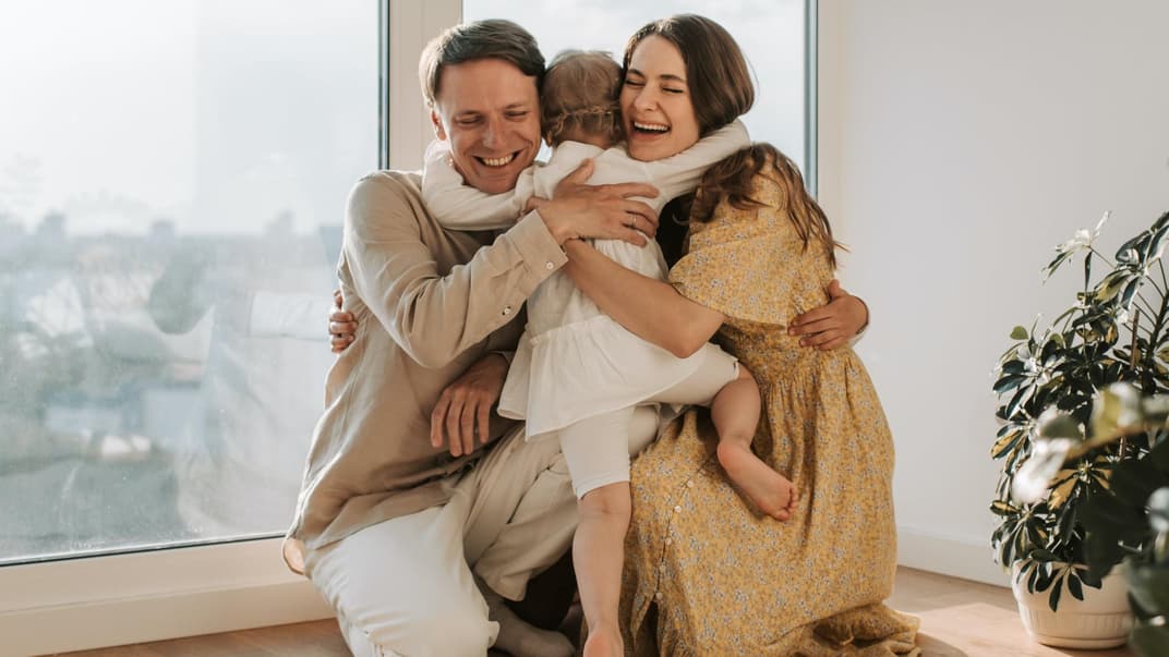 Kleines Kind umarmt glückliche Eltern.