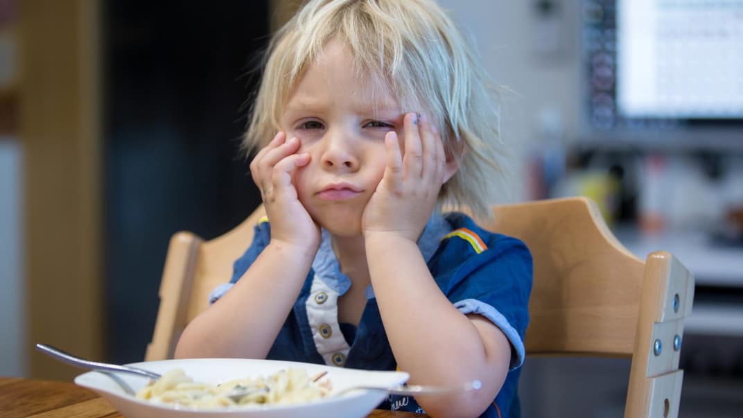 Kleiner, blonder Junge ist enttäuscht von seinem Essen. 