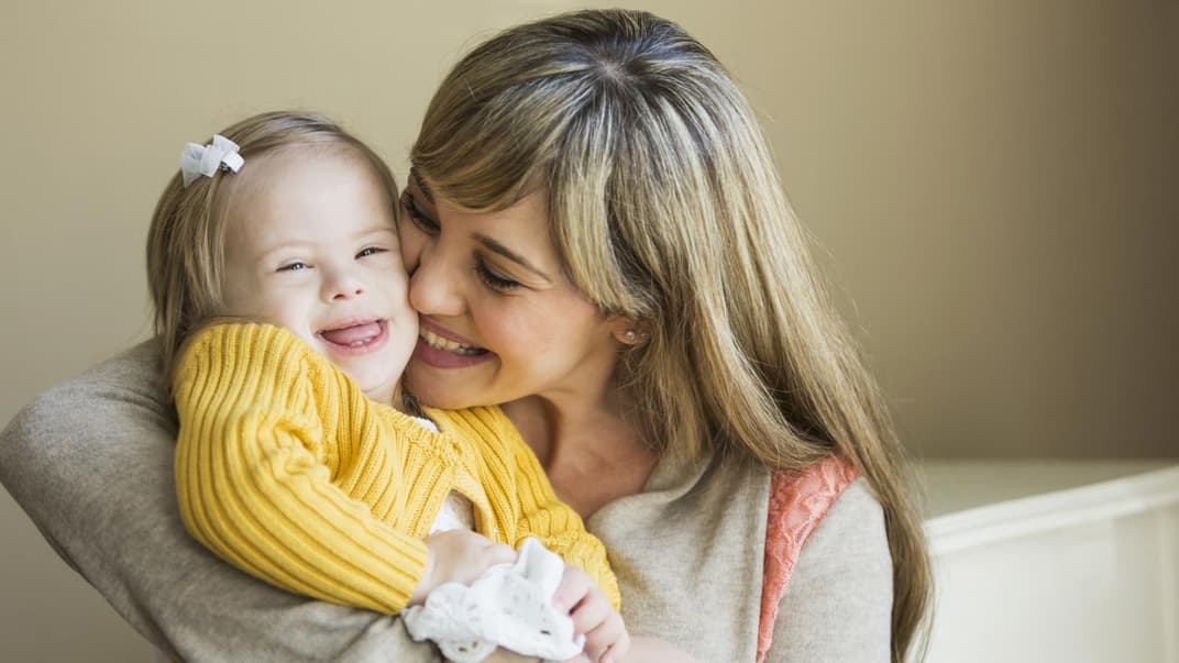 Eine Mutter kuschelt mit ihrer Tochter, die das Down-Syndrom hat.