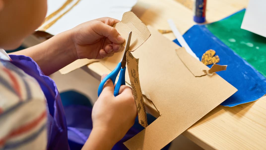 Kind bastelt mit Pappkarton eine Paw Patrol-Figur.