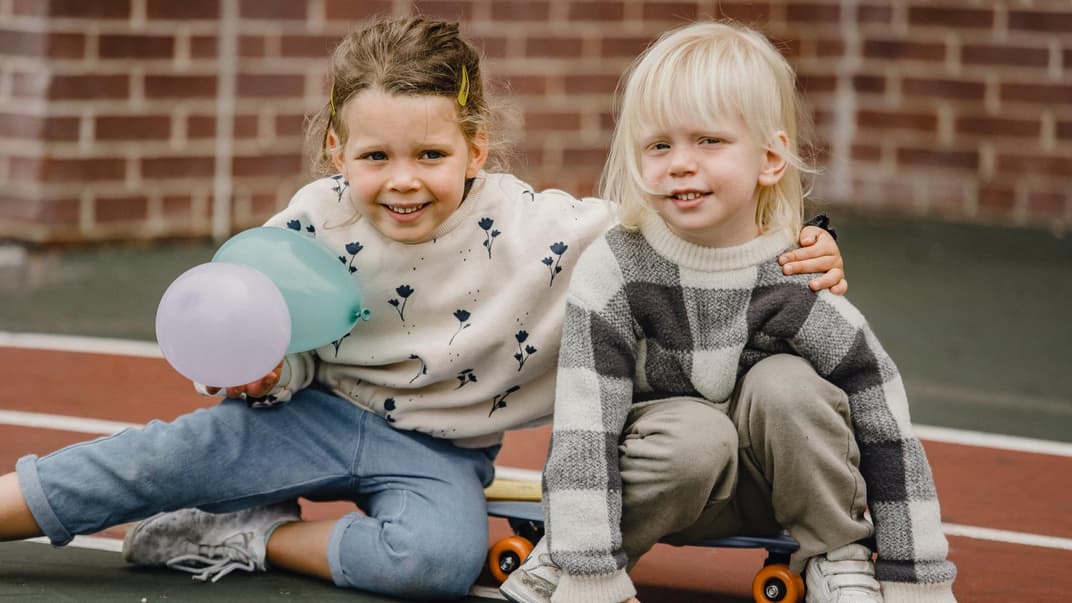 Ein Mädchen und ein Junge auf einem Skateboard draußen