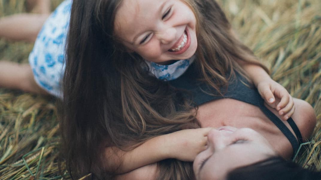 Glückliches Mädchen liegt mit seiner Mutter im Feld.