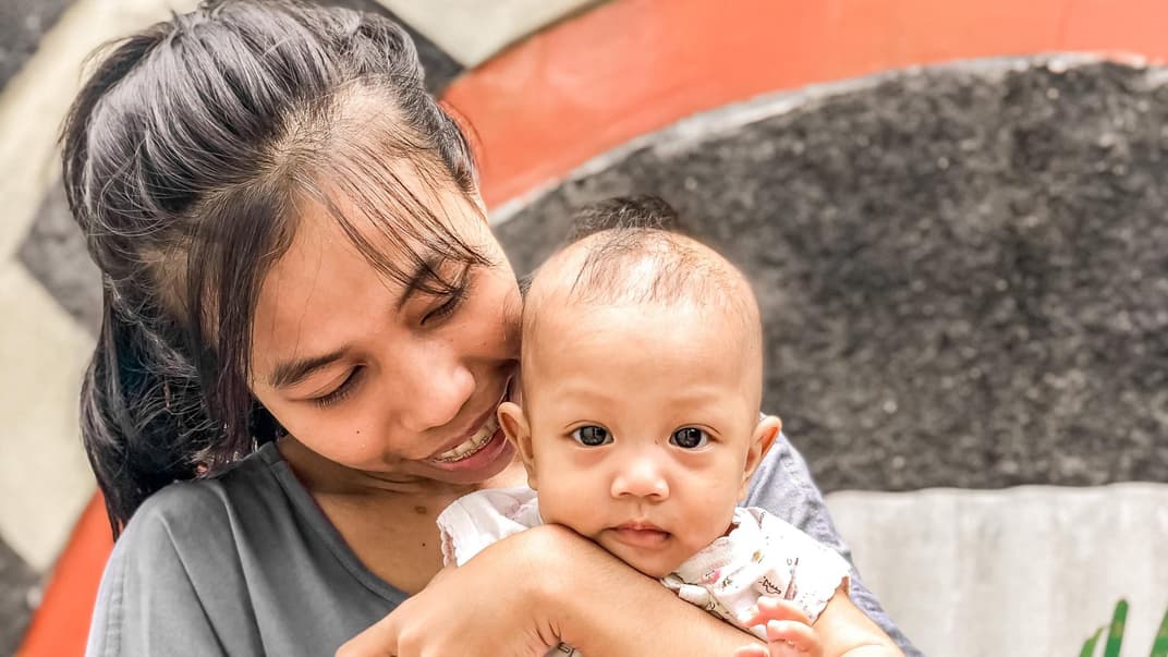 Junge Frau mit Baby auf dem Arm.