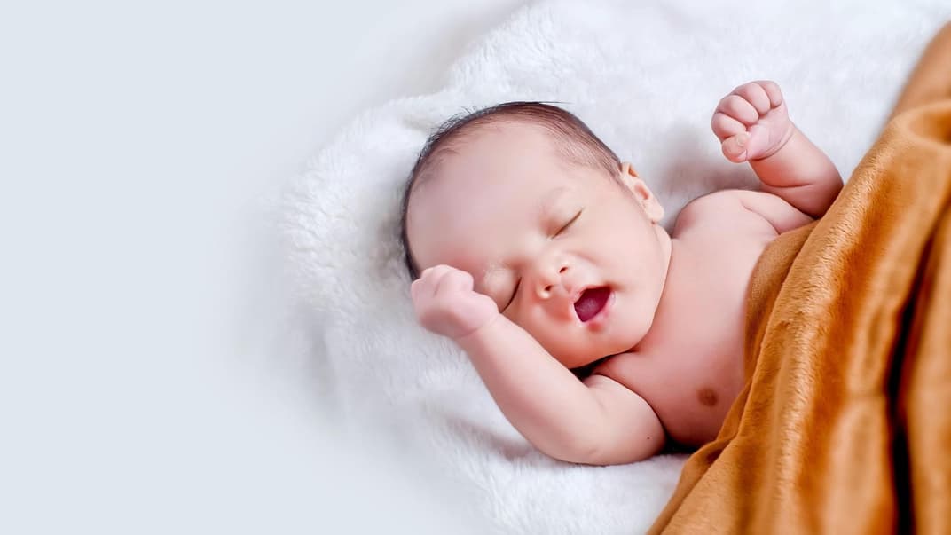 Baby, das auf weißem Fell mit brauner Decke liegt