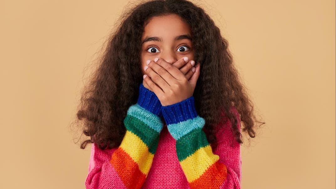 Erstauntes Mädchen hält sich die Hände vor den Mund