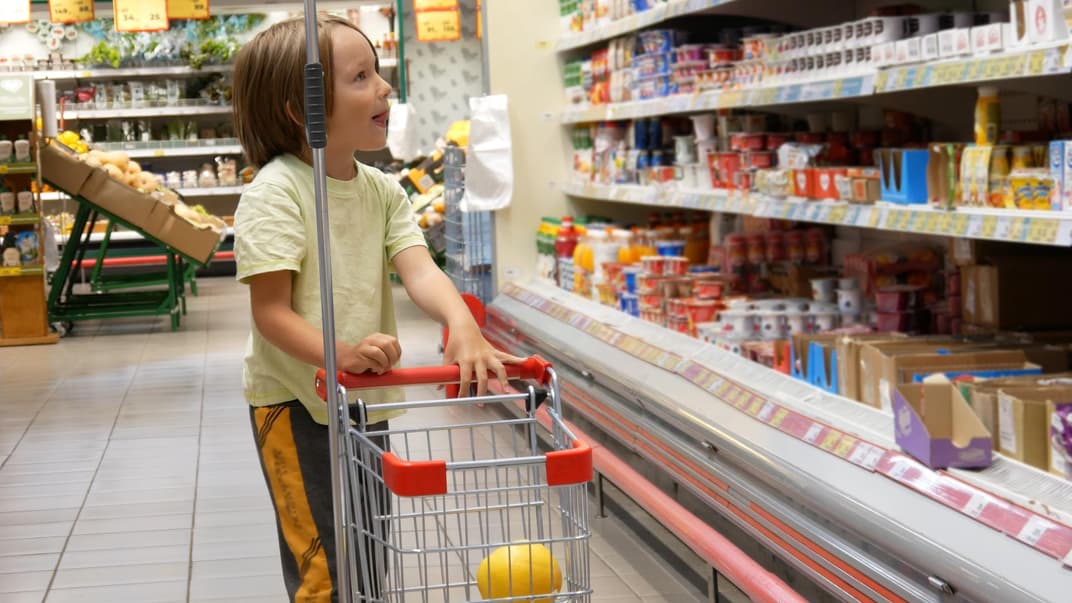 Kinder lieben die kleinen Einkaufswagen in Supermärkten Ein Junge im Supermarkt mit kleinem Einkaufswagen