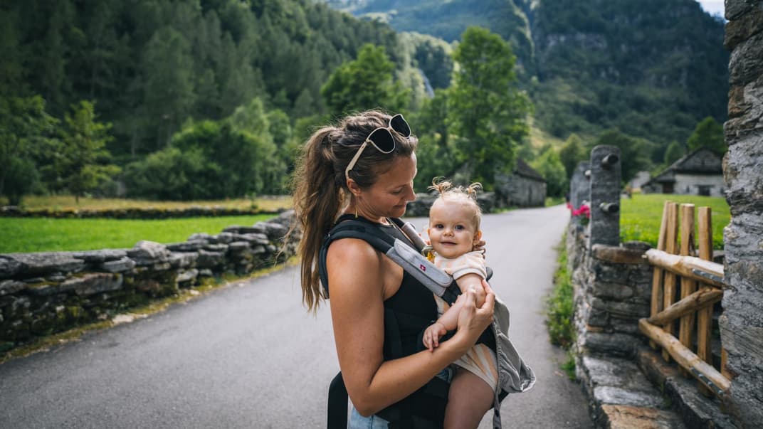 Mutter mit Baby in der Trage in den Bergen