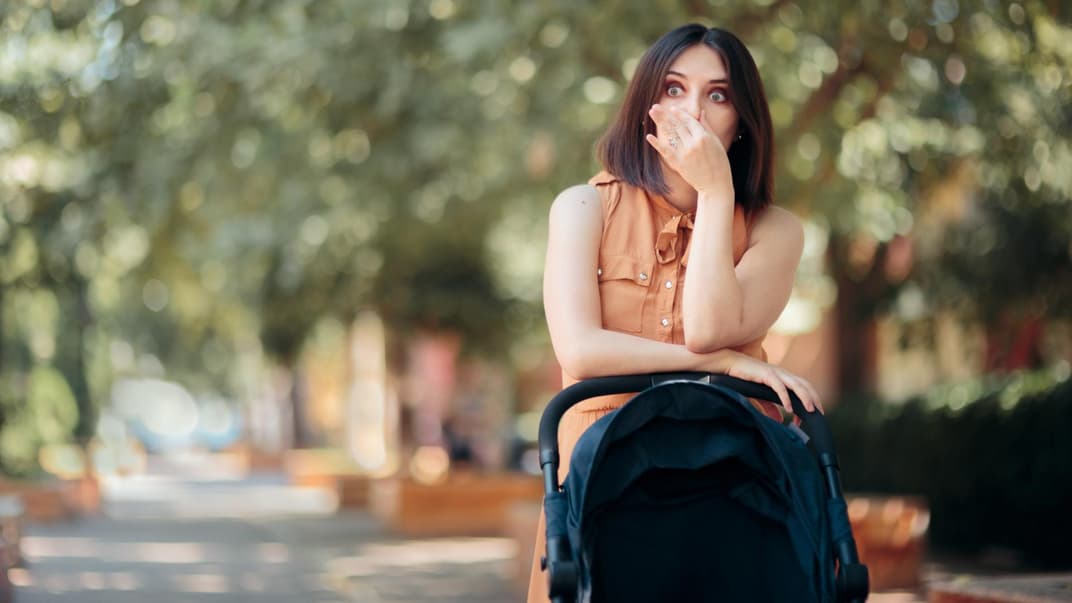 Mutter mit Buggy hält sich die Nase zu.