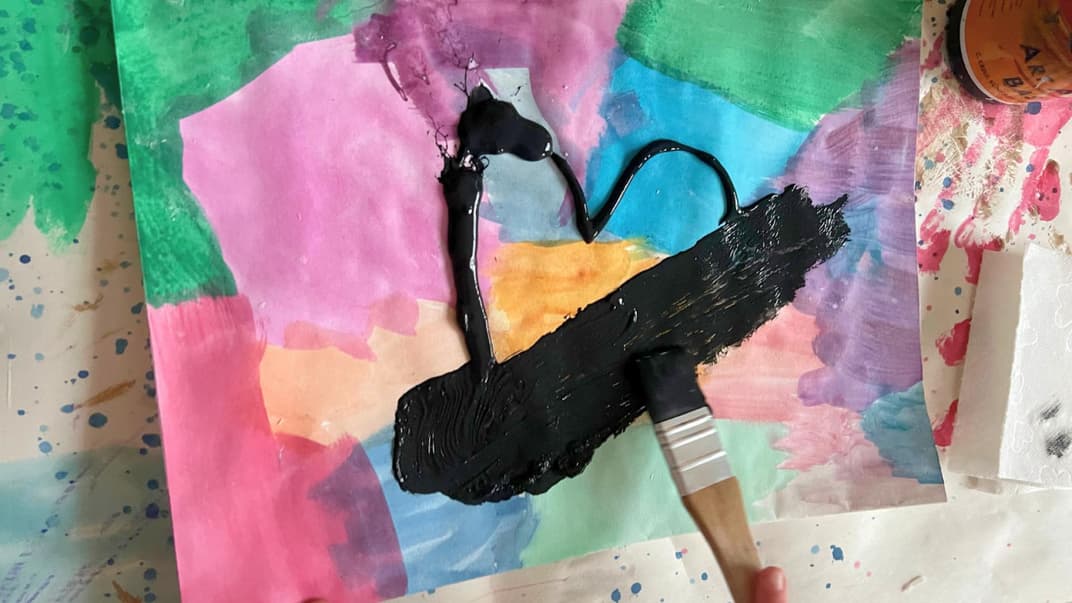 Bunt getuschtes Papier wird mit einer schwarzen Schicht Acrylfarbe übermalt