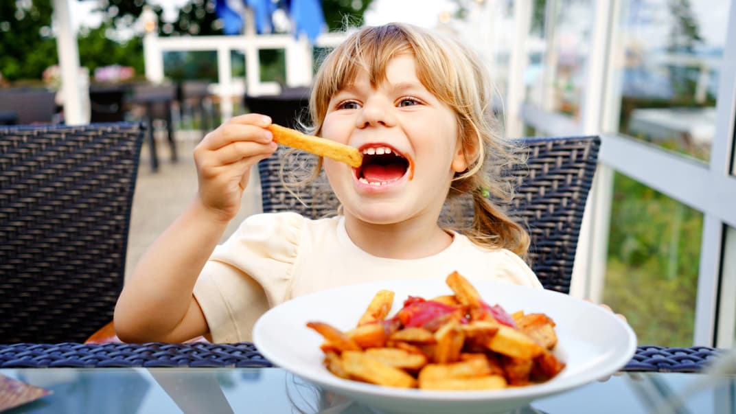 Ein kleines Mädchen isst Pommes.