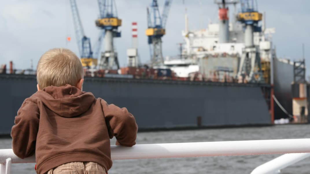 Junge bestaunt Schiff am Hamburger Hafen.