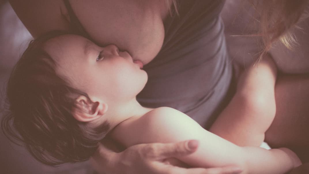 Ein kleines Kind, das von seiner Mutter gestillt wird. 