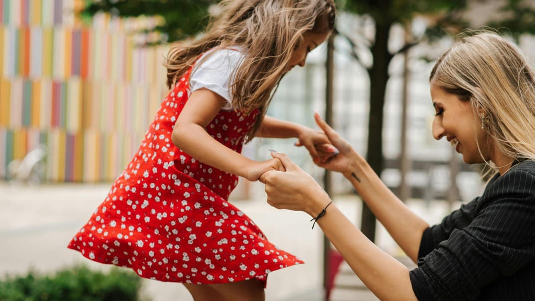 Mutter hilft ihrer Tochter, von etwas herunterzuspringen.