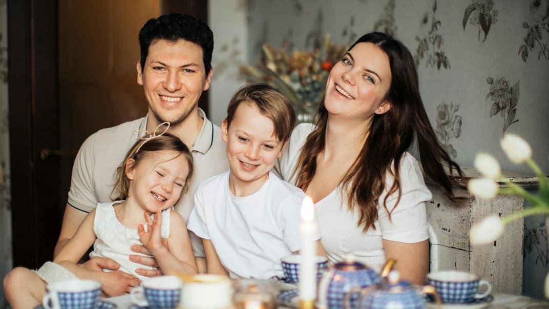 Eine glückliche, vierköpfige Familie ist abgebildet.