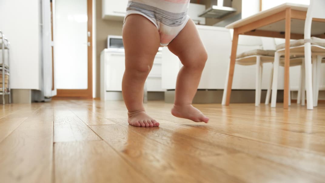 Babybeine beim Laufen in der Küche.