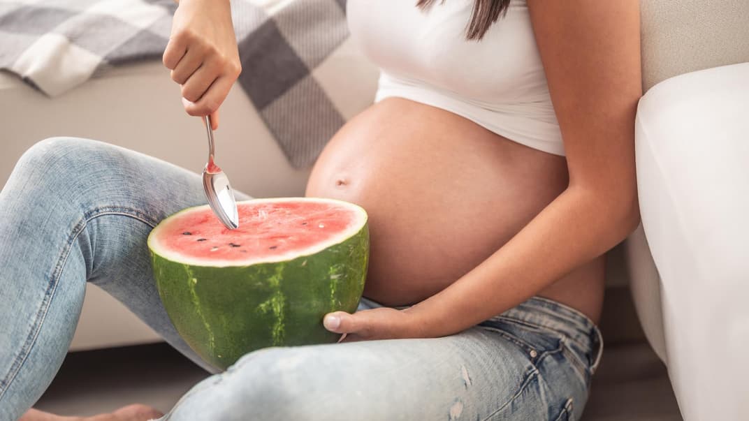 Schwangere löffelt Wassermelone.