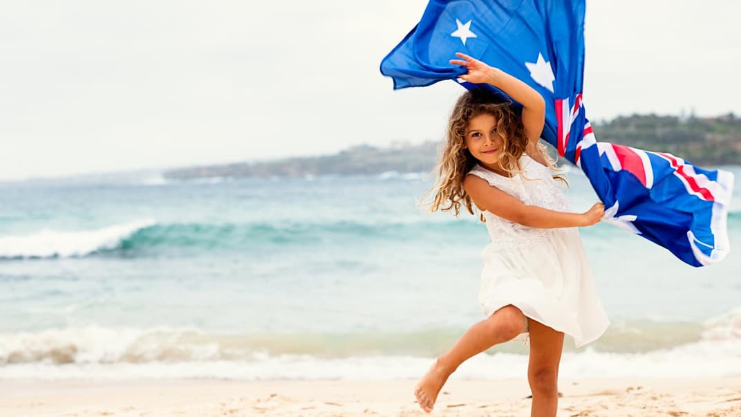 Ein Mädchen mit australischer Flagge am Strand. 