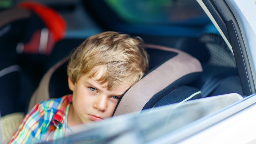 Ein kleiner Junge schaut aus dem offenen Autofenster. 