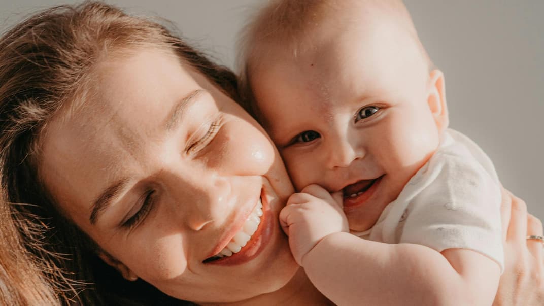 Glückliche Mutter mit süßem Baby auf dem Arm.