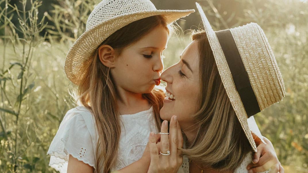 Eine Tochter gibt ihrer Mutter einen Kuss auf die Nase.